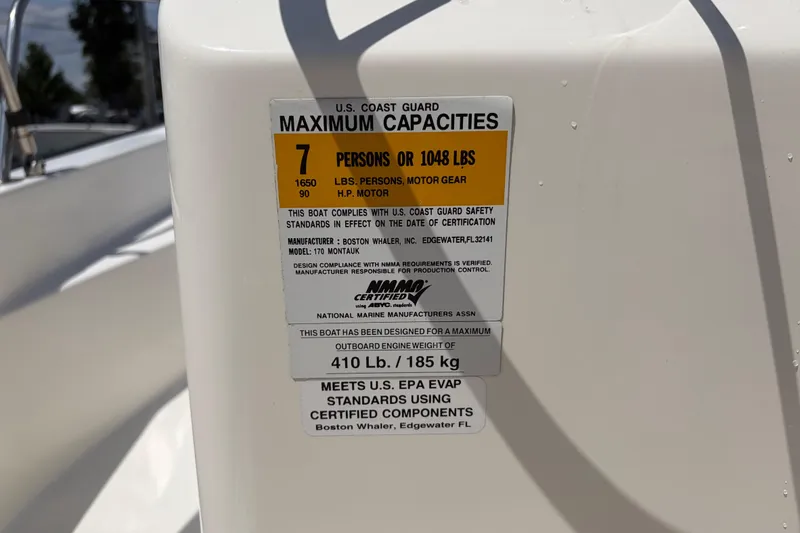 Slide: The Image of 2012 Boston Whaler 170 Montauk capacity label, 7 persons or 1048 lbs, safety compliance. - 19