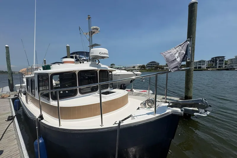 Slide: The Image of 2017 Ranger Tugs R-27 docked at marina, clear sky, waterfront buildings in background. - 21