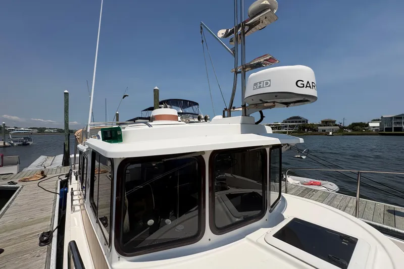 Slide: The Image of 2017 Ranger Tugs R-27 docked, featuring Garmin radar, clear skies, and waterfront homes. - 10