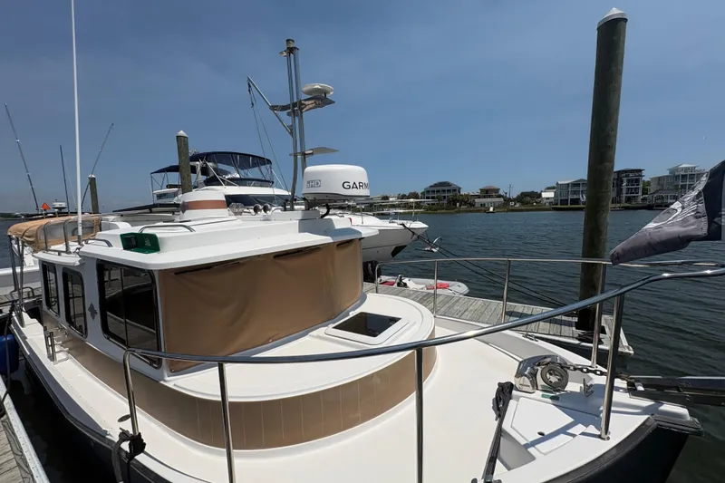 Slide: The Image of 2017 Ranger Tugs R-27 docked at a marina, clear sky, waterfront homes in background. - 13