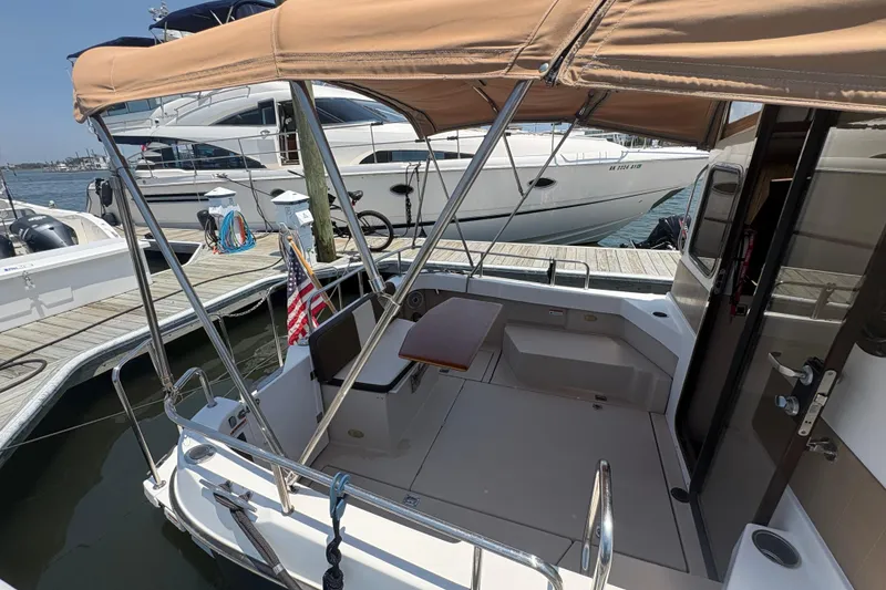 Slide: The Image of 2017 Ranger Tugs R-27 boat docked, featuring a covered seating area and American flag. - 25