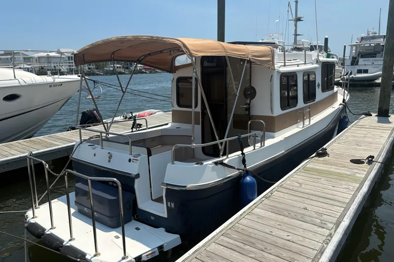 Slide: The Image of 2017 Ranger Tugs R-27 boat docked at marina with tan canopy. - 4