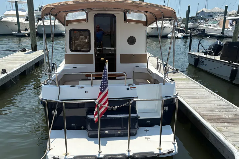 Slide: The Image of 2017 Ranger Tugs R-27 docked, featuring rear view with American flag. - 2