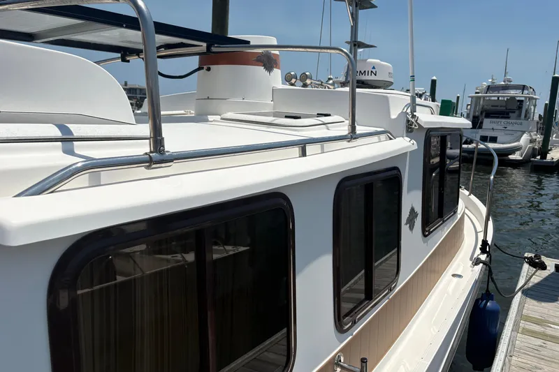 Slide: The Image of 2017 Ranger Tugs R-27 docked at a marina, showcasing its sleek design and windows. - 12