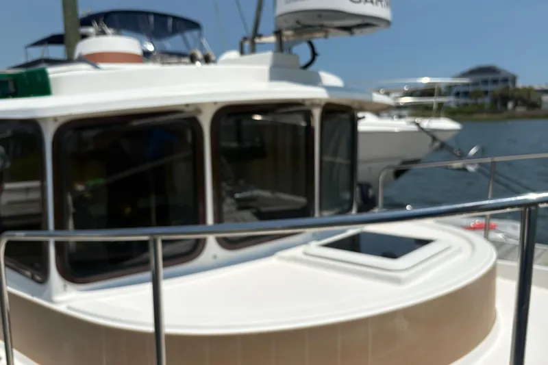 Slide: The Image of 2017 Ranger Tugs R-27 boat docked by the water, featuring cabin windows. - 11