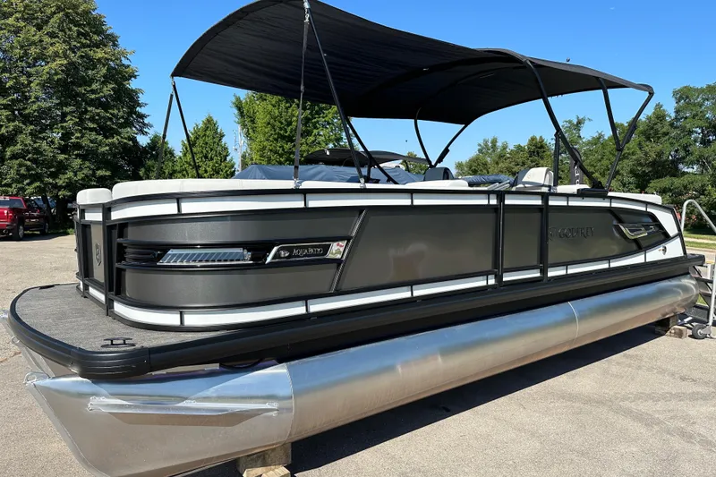 The Image of 2025 Godfrey AquaPatio 255 SB pontoon boat with canopy, parked outdoors on a sunny day. - 0