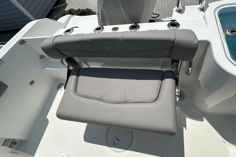 Slide: The Image of 2020 Wellcraft 222 Fisherman boat seating area with gray cushioned bench and rod holders. - 10