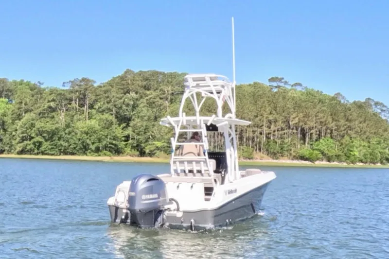 Slide: The Image of 2020 Wellcraft 222 Fisherman boat on a serene lake with forested shoreline. - 11
