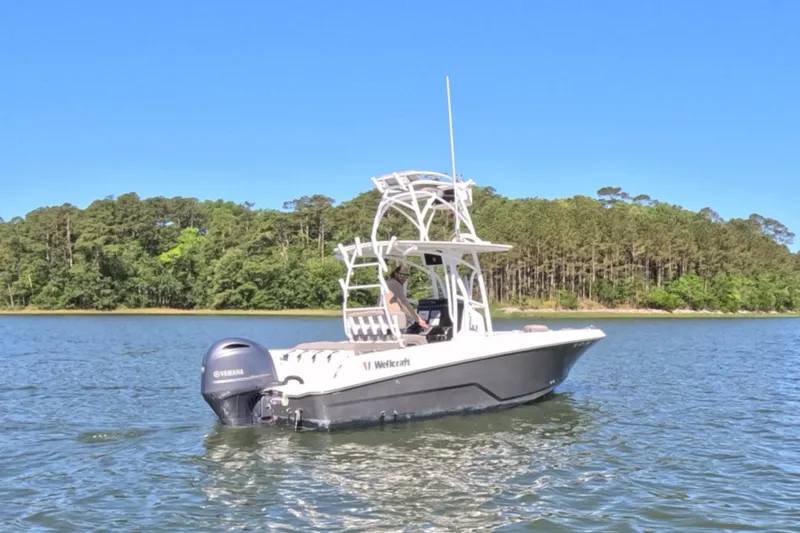 Slide: The Image of 2020 Wellcraft 222 Fisherman boat on a serene lake with forested shoreline. - 12