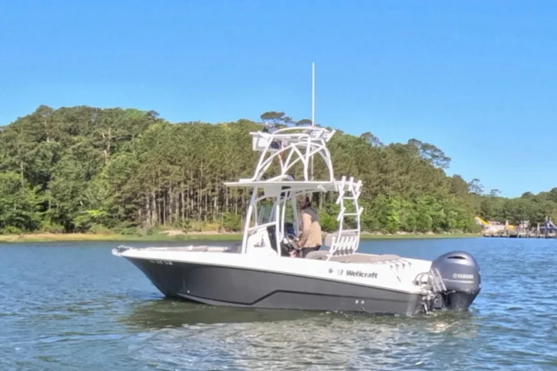 Slide: The Image of 2020 Wellcraft 222 Fisherman boat cruising on a scenic lake with forested shoreline. - 3