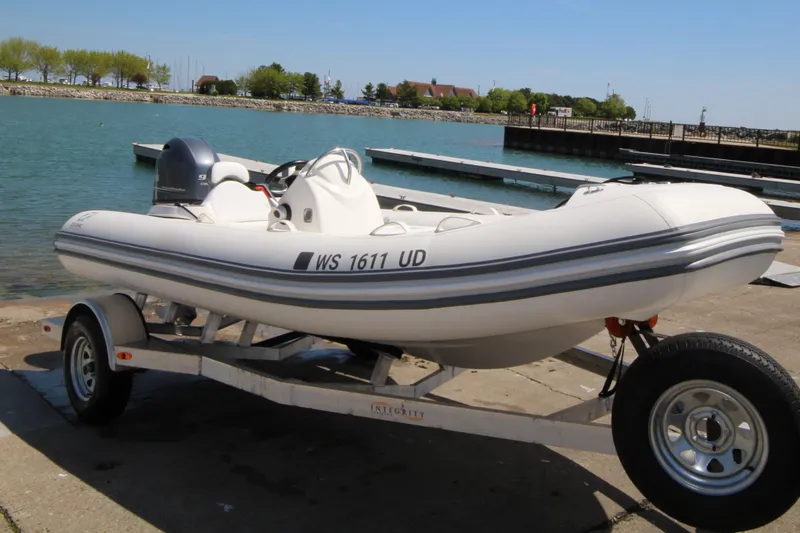 Slide: The Image of 2023 Zodiac Yachtline 490 inflatable boat on trailer by a lakeside dock. - 10