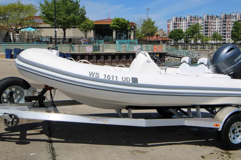 Slide: The Image of 2023 Zodiac Yachtline 490 on trailer, dockside with urban backdrop. - 6
