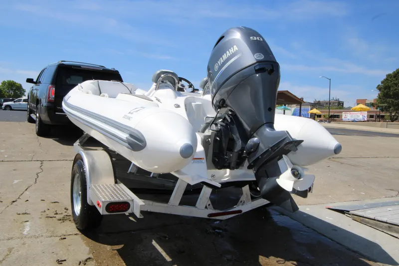 Slide: The Image of 2023 Zodiac Yachtline 490 on trailer with Yamaha outboard motor, parked near SUV. - 7