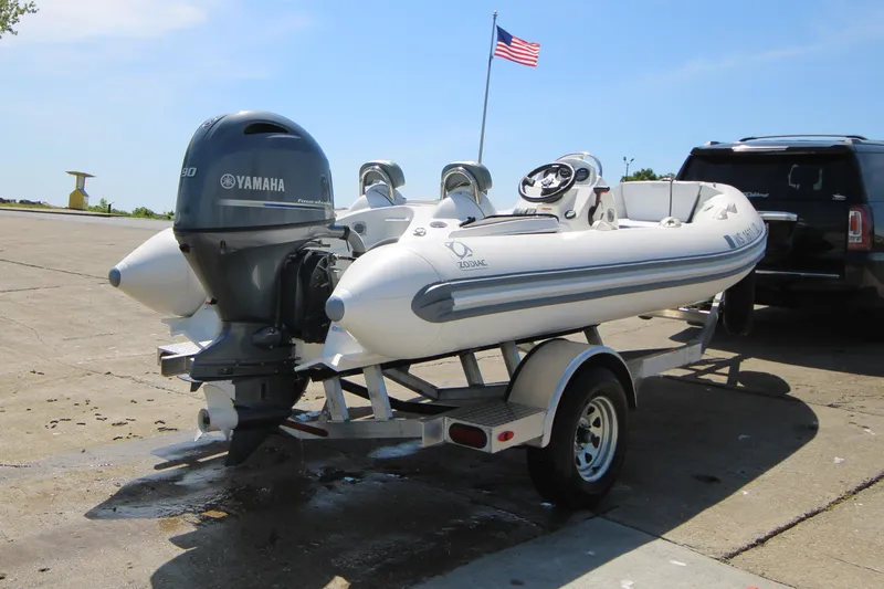 Slide: The Image of 2023 Zodiac Yachtline 490 boat on trailer with Yamaha engine, parked near American flag. - 9