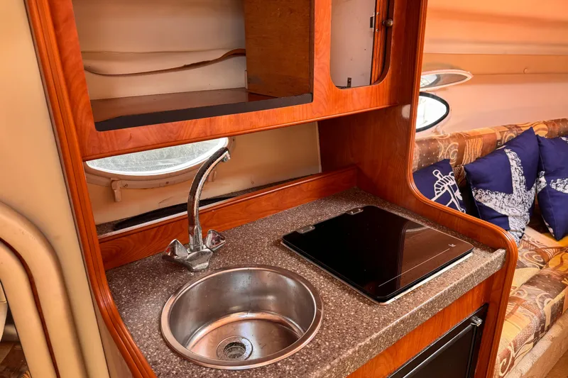 Slide: The Image of 2004 Rinker Fiesta Vee 270 cabin interior with kitchenette and seating area. - 12