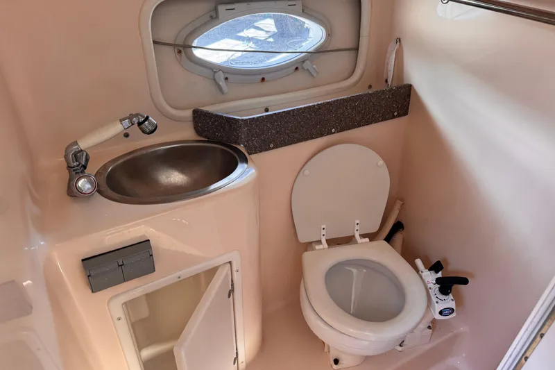 Slide: The Image of 2004 Rinker Fiesta Vee 270 boat bathroom with sink, toilet, and porthole window. - 13