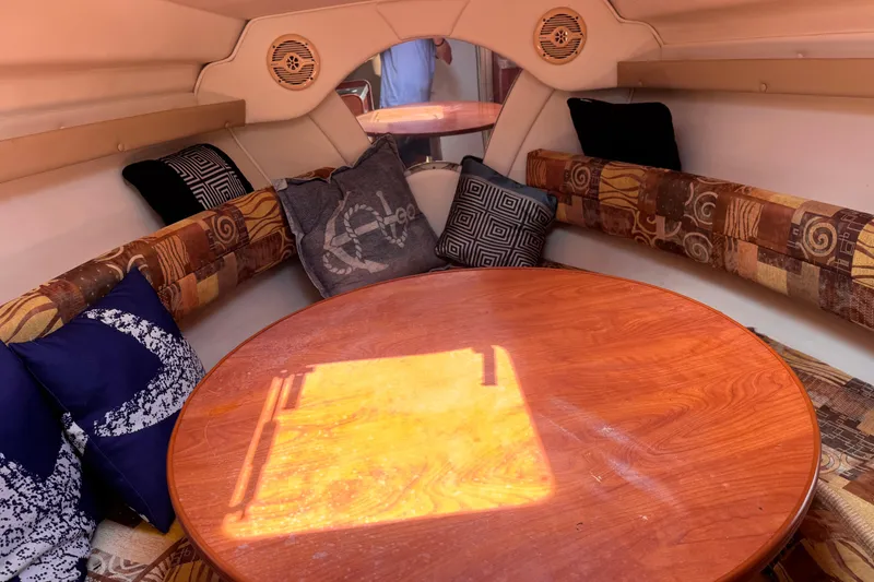 Slide: The Image of 2004 Rinker Fiesta Vee 270 cabin interior with round wooden table and patterned cushions. - 14