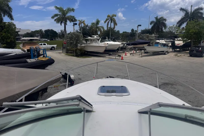 Slide: The Image of 2004 Rinker Fiesta Vee 270 docked, surrounded by boats and palm trees under a blue sky. - 17