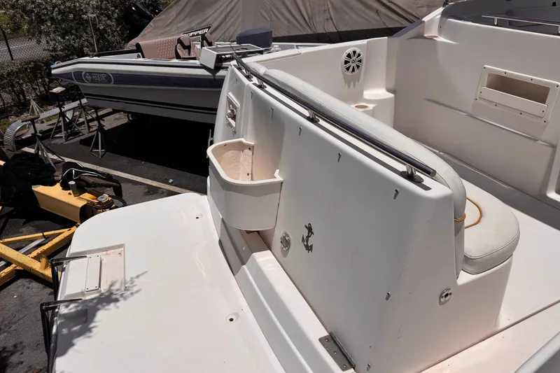 Slide: The Image of 2004 Rinker Fiesta Vee 270 boat deck with seating and storage, parked outdoors. - 6