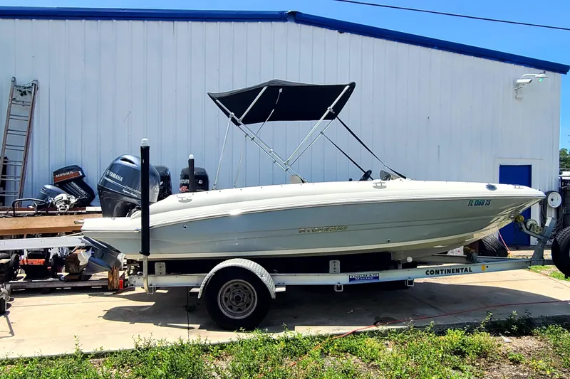 The Image of 2023 Stingray 182 SC boat on trailer, parked outside a white building. - 0