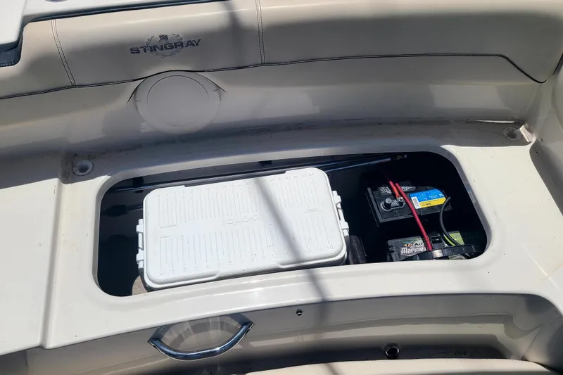 Slide: The Image of 2023 Stingray 182 SC boat storage compartment with cooler and marine battery. - 12