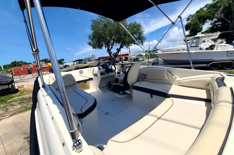 Slide: The Image of 2023 Stingray 182 SC boat interior with seating and steering wheel under a sunny sky. - 13