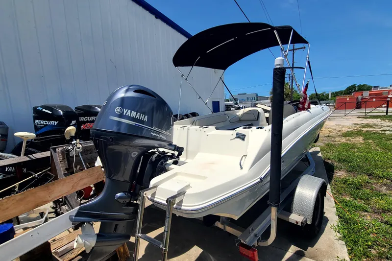 Slide: The Image of 2023 Stingray 182 SC boat with Yamaha engine on trailer, parked outdoors. - 14