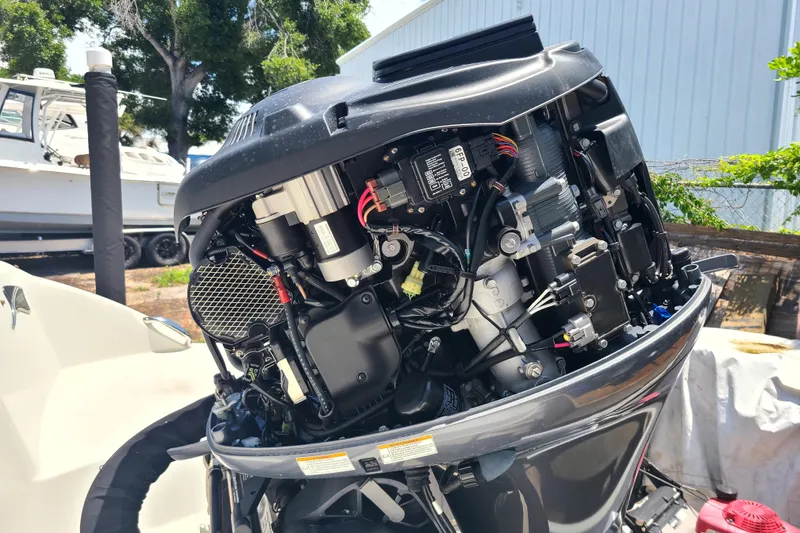 Slide: The Image of 2023 Stingray 182 SC boat engine, detailed view, outdoors with other boats in background. - 17