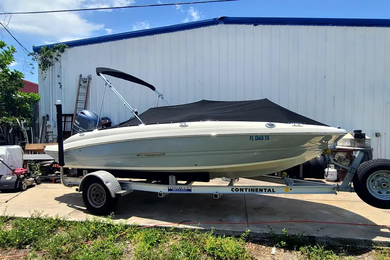 Slide: The Image of 2023 Stingray 182 SC boat on trailer, parked outdoors near a white building. - 18