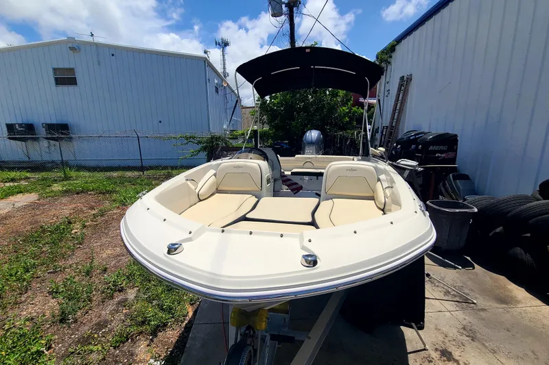 Slide: The Image of 2023 Stingray 182 SC boat with beige seating, parked outdoors under a blue sky. - 2