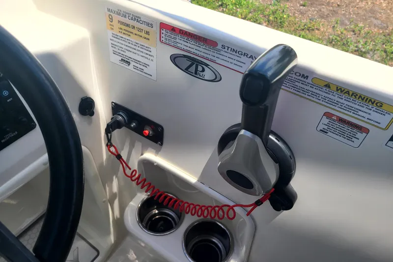 Slide: The Image of 2023 Stingray 182 SC boat controls with throttle, warning labels, and cup holders. - 8