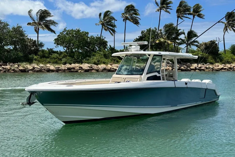 The Image of 2019 Boston Whaler 380 Outrage boat on calm water with palm trees in background. - 1