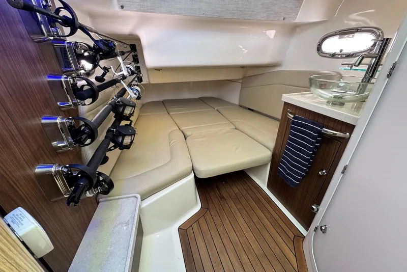 Slide: The Image of 2019 Boston Whaler 380 Outrage cabin with fishing rods, cushioned seating, and modern sink. - 18