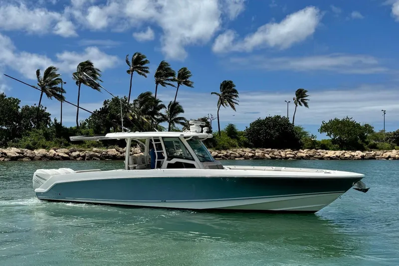 Slide: The Image of 2019 Boston Whaler 380 Outrage boat cruising on a sunny day with palm trees in the background. - 5