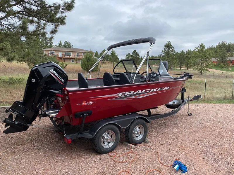 The Image of Red 2021 Tracker Pro Guide boat parked on trailer outdoors. - 0