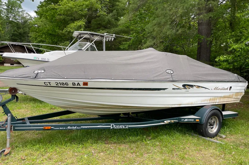 The Image of Covered 2000 Mariah 202 Shabah boat on trailer, parked in a wooded area. - 0