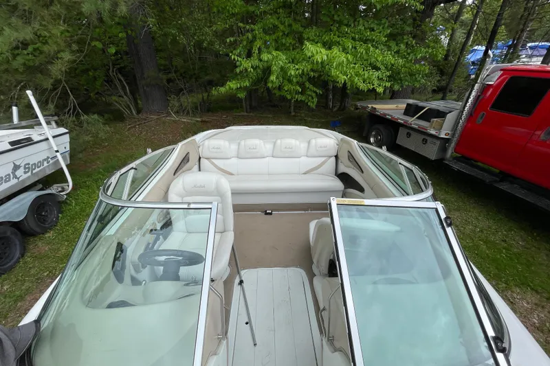 Slide: The Image of 2000 Mariah 202 Shabah boat with white interior, parked near trees and vehicles. - 6