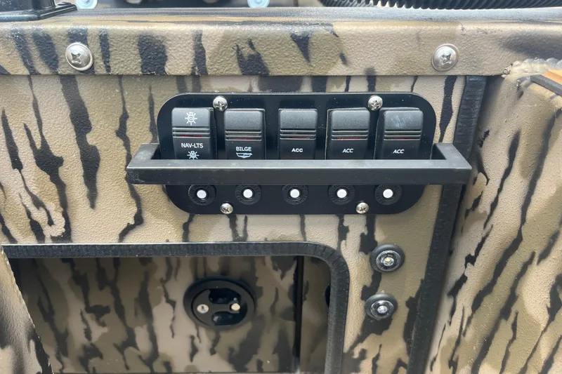 Slide: The Image of Control panel of Excel 1854 F4 Pro 2026 boat with switches and camouflage design. - 14