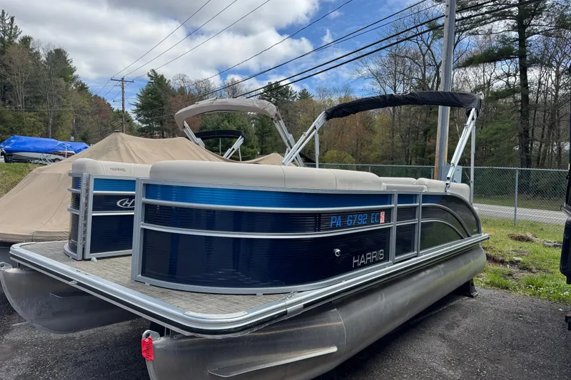 Slide: The Image of 2023 Harris Cruiser 210 CW pontoon boat parked outdoors on a cloudy day. - 6