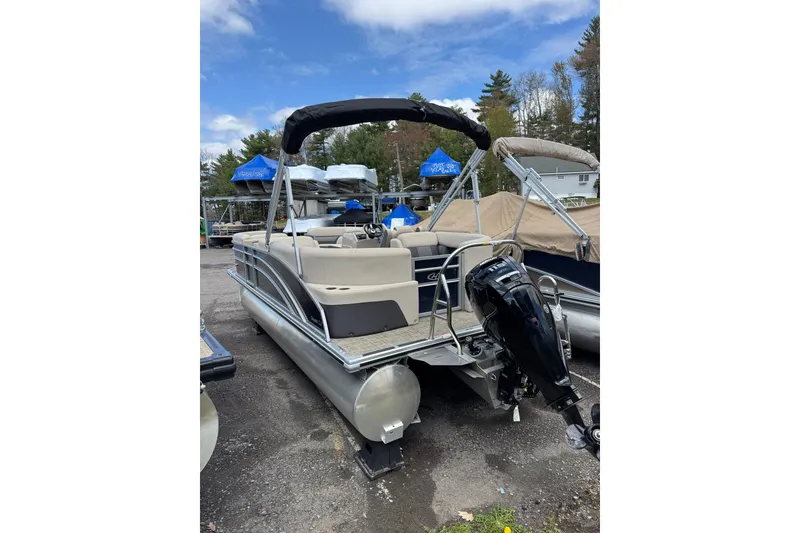 Slide: The Image of 2023 Harris Cruiser 210 CW pontoon boat with outboard motor, parked outdoors. - 7