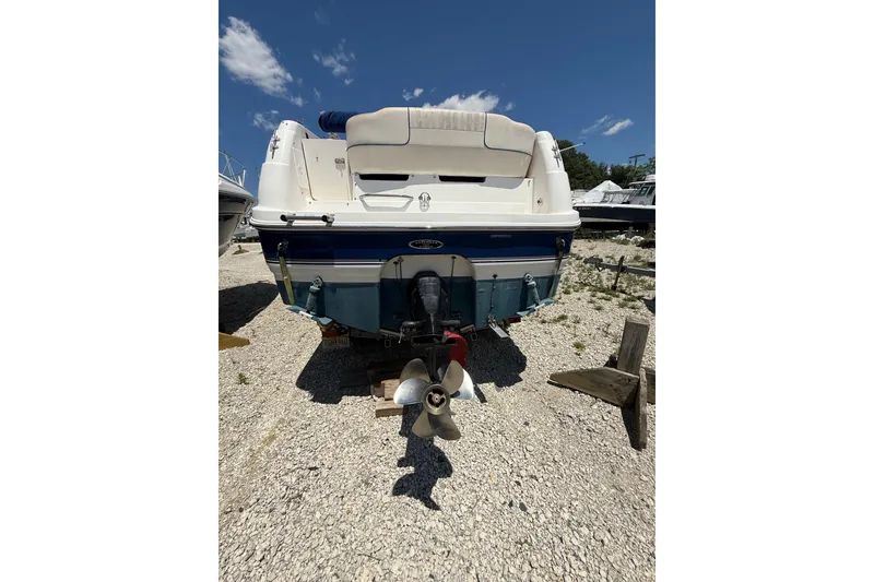 Slide: The Image of Rear view of a 2000 Chaparral Signature 240 boat on gravel, under a clear sky. - 10