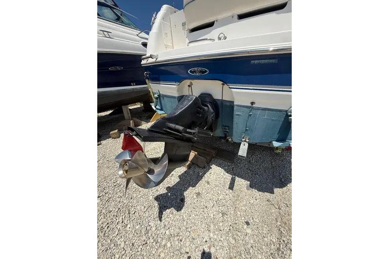 Slide: The Image of 2000 Chaparral Signature 240 boat stern with propeller, parked on gravel. - 12