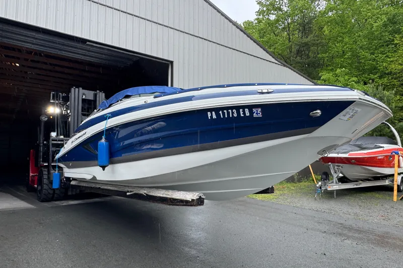 Slide: The Image of 2022 Crownline Eclipse E255 boat being moved by a forklift outside a storage facility. - 18