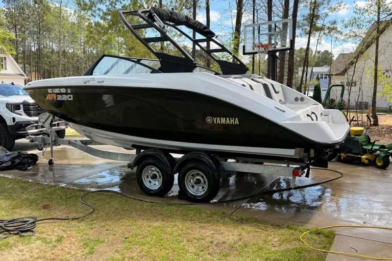 The Image of 2024 Yamaha AR220 boat on trailer in residential driveway setting. - 1