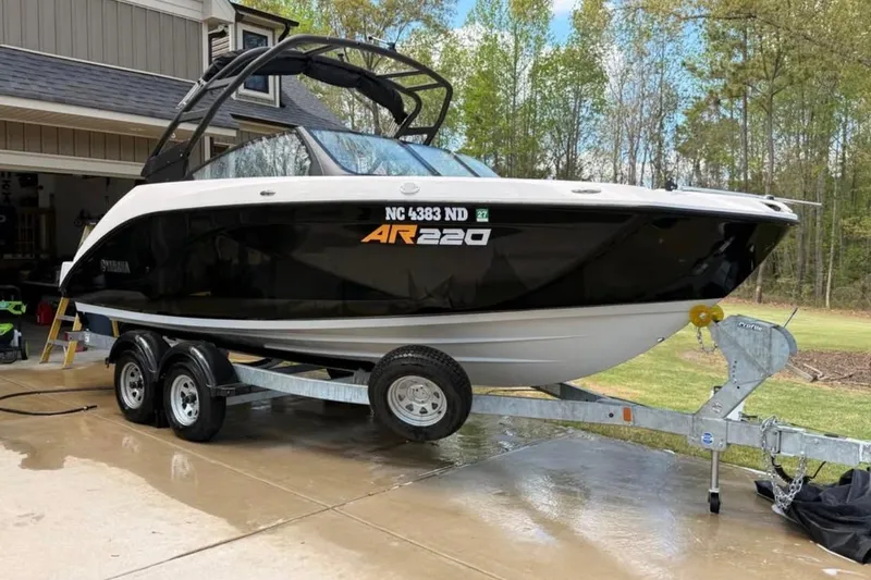 Slide: The Image of 2024 Yamaha Boats AR220 on trailer, parked in driveway near house and trees. - 4
