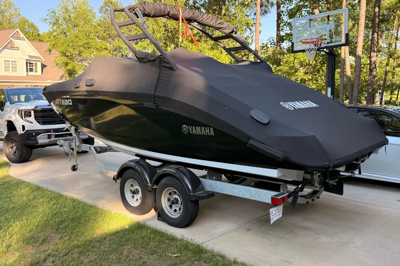 Slide: The Image of 2024 Yamaha AR220 boat on trailer, covered, parked in driveway. - 6