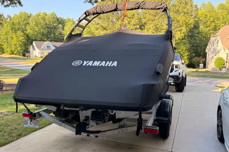 Slide: The Image of 2024 Yamaha AR220 boat covered on trailer in suburban driveway. - 7