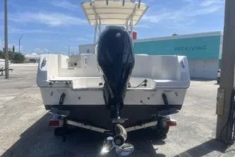 Slide: The Image of 2022 Sailfish 242 CC boat with outboard motor, parked on a trailer in a sunny lot. - 6