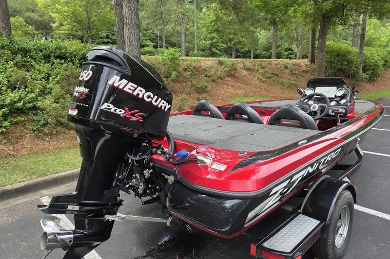 Slide: The Image of Red 2011 Nitro Z-7 boat with Mercury Pro XS engine in a wooded parking area. - 3