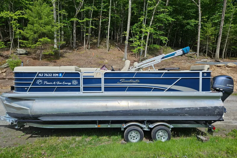 The Image of 2019 Sweetwater 2086 pontoon boat on trailer, parked in wooded area. - 1